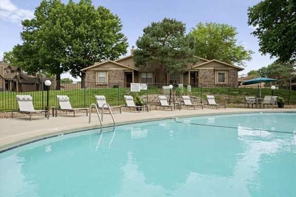 A pool with chairs around it and the Waterford Place Apartments & Townhomes clubhouse in the background.