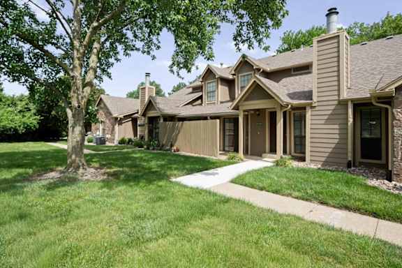 Exterior view of a residential building at Waterford Place Apartments & Townhomes, featuring a mature shade tree and plenty of green space