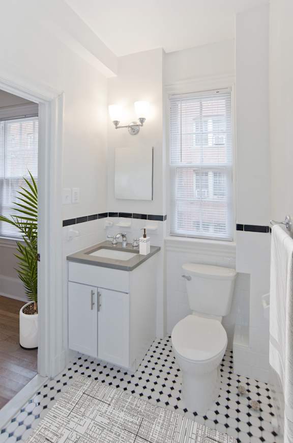 A white toilet sits in a bathroom with a black and white floor.
