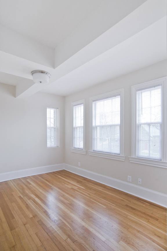 an empty room with a hard wood floor and three windows