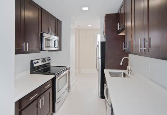 A kitchen with brown cabinets and white countertops.