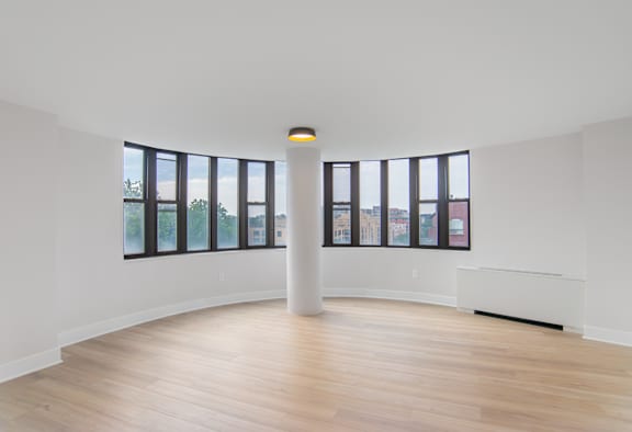 A white room with a large window and a white column in the middle.