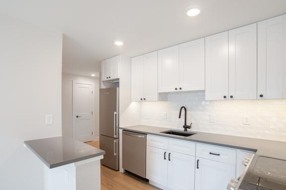 A kitchen with white cabinets and a grey counter top.