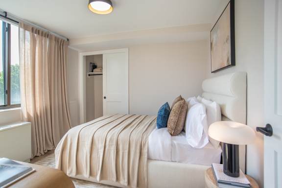 A bedroom with a large bed and a lamp on the side table.