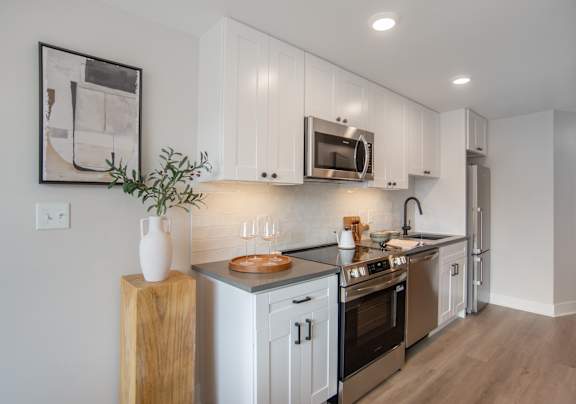 A modern kitchen with white cabinets and stainless steel appliances.