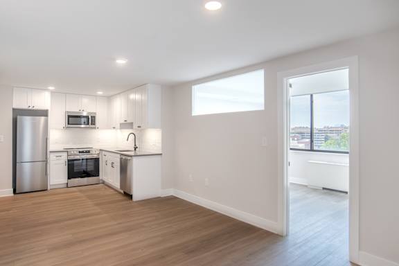 A kitchen with white cabinets and a stainless steel refrigerator.