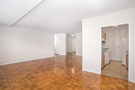 a living room and kitchen with wood flooring and white walls
