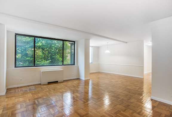 an empty living room with wood floors and a large window
