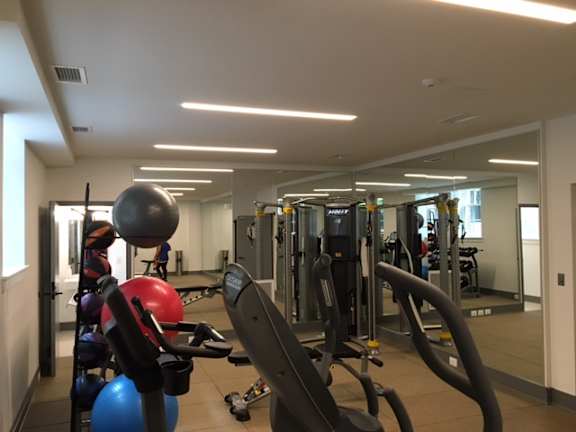 A gym with a variety of equipment including treadmills, weights, and exercise balls.