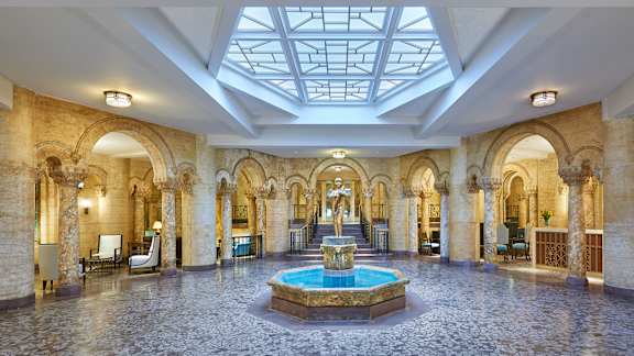 A large, ornate room with a fountain in the middle and a skylight above.