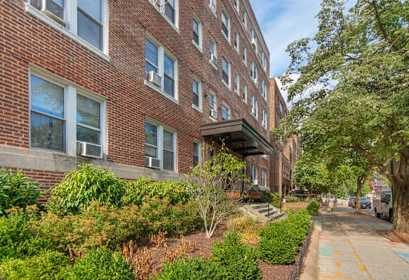 A brick building with a green bush in front of it.