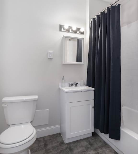 a bathroom with a white toilet and a black shower curtain