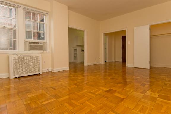 A room with a wooden floor and a window with a radiator.