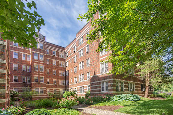 A large brick building with a garden in front.
