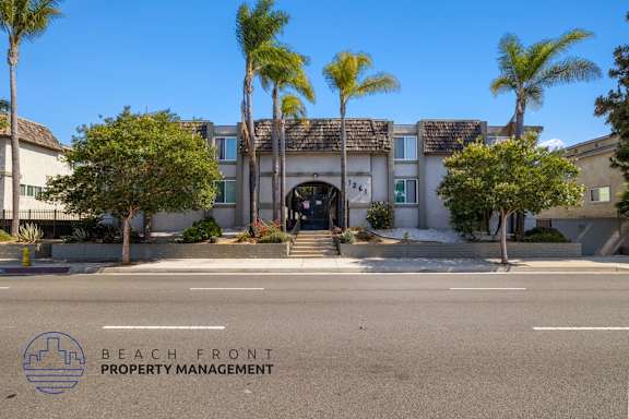 A building with palm trees in front of it and the words "Beach Front Property Management" on the bottom left.