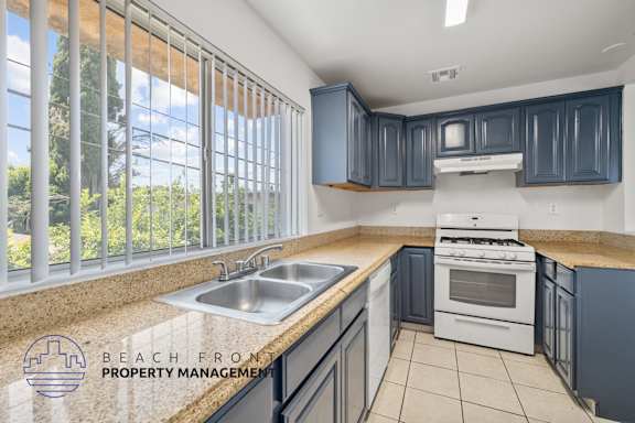 a kitchen with blue cabinets and white appliances and a sink