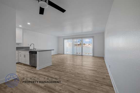 A spacious room with a kitchen area and a ceiling fan.