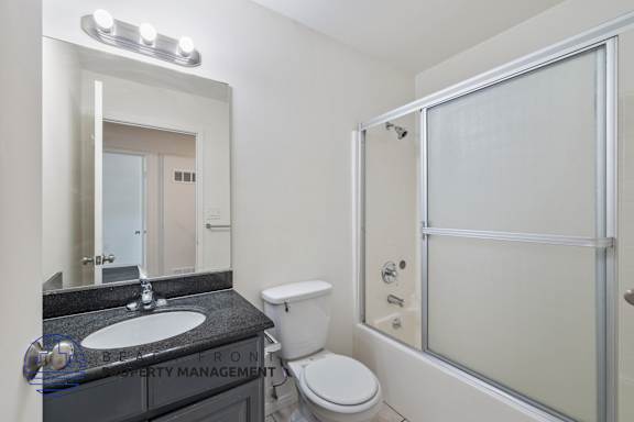 a bathroom with a shower toilet and sink and a mirror