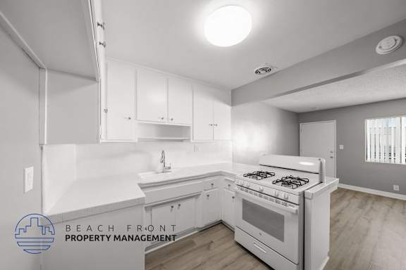Floor Plan  A modern kitchen with a stove top oven and white cabinets.