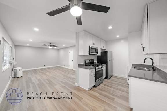 A spacious kitchen and living room with a fan and a refrigerator.