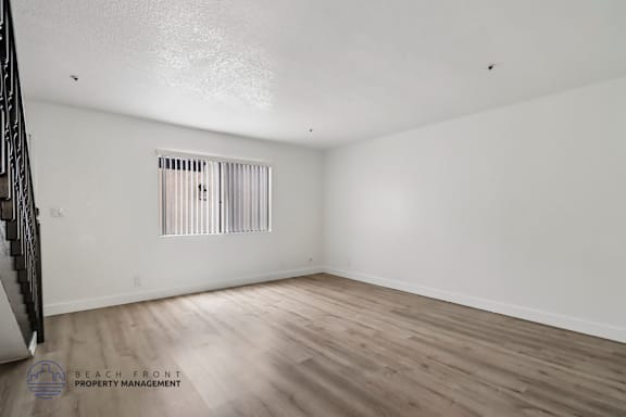 A room with wooden flooring and a window with blinds.