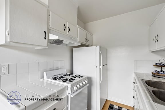 A kitchen with white cabinets and appliances.