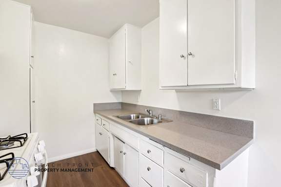 A kitchen with white cabinets and a stove top oven.
