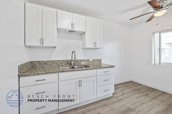 A kitchen with white cabinets and a granite countertop.