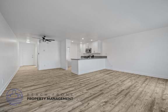 A spacious room with wooden flooring and a ceiling fan.