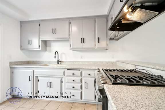 A kitchen with white cabinets and a stove top oven.