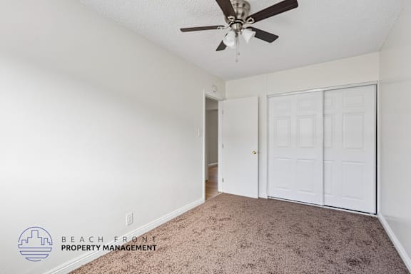 A room with a ceiling fan and carpeted floor.