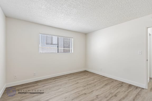 A room with a window and wooden flooring.