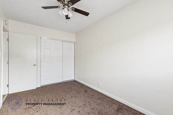 A room with a ceiling fan and a carpeted floor.