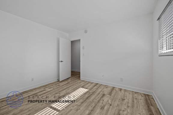 A room with a wooden floor and a door on the left side.