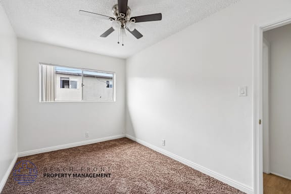 A room with a ceiling fan and a window with blinds.