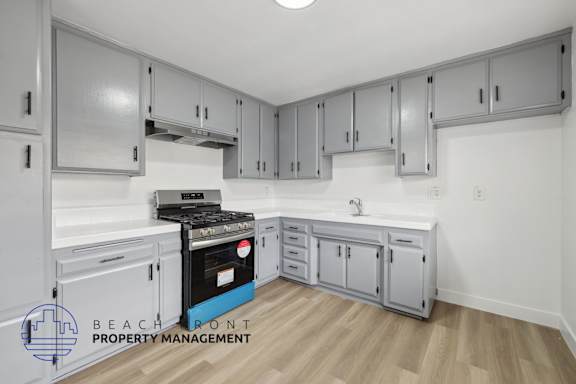 A kitchen with a stove top oven and a sink.