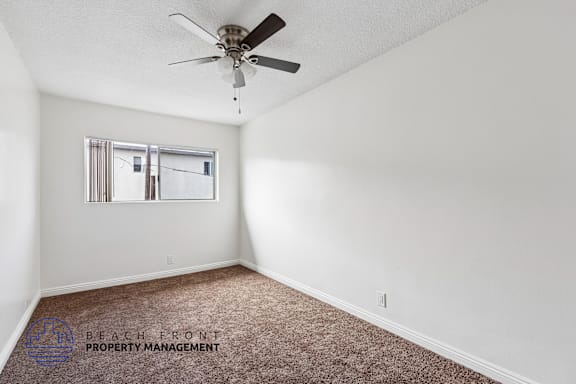 A room with a ceiling fan and carpeted floor.