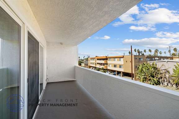 A balcony with a view of a building and trees.