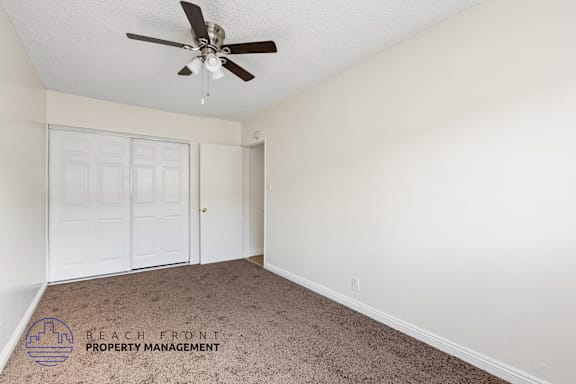 A room with a ceiling fan and carpeted floor.