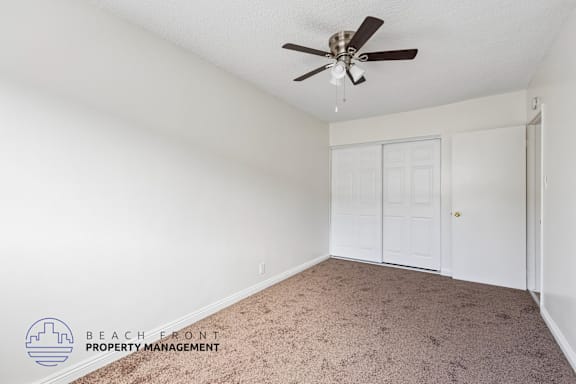 A room with a carpet floor and a ceiling fan.