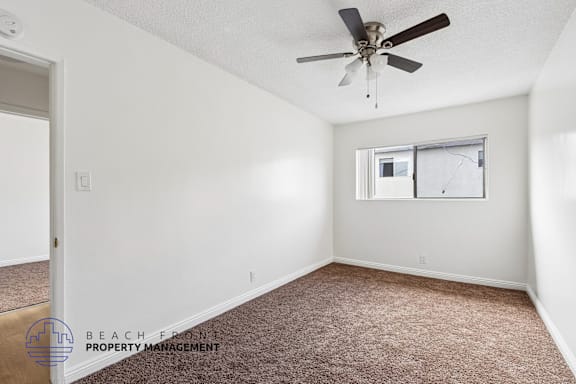 A room with a ceiling fan and a window with a screen door.