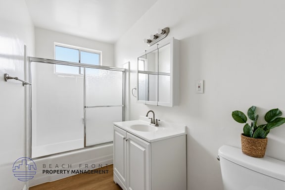 A white bathroom with a sink, mirror, and bathtub.