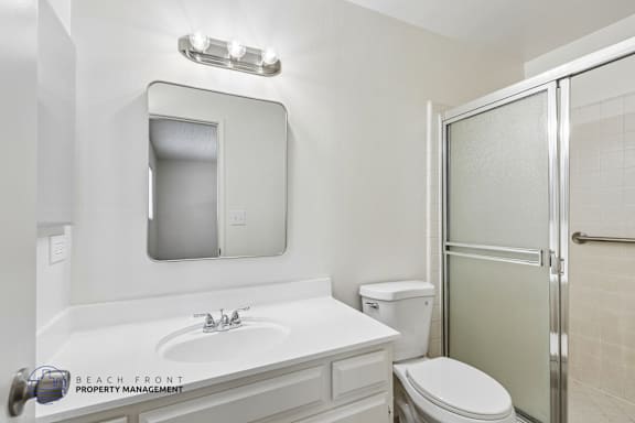 A white bathroom with a sink, toilet and shower.
