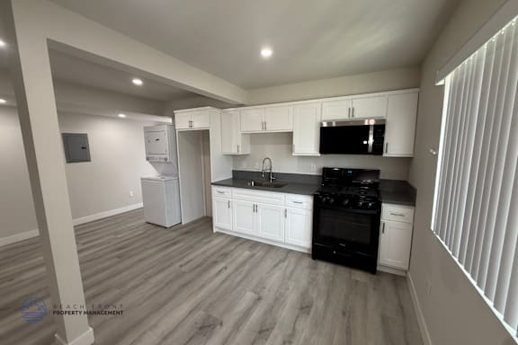 Floor Plan  A kitchen with black appliances and white cabinets.