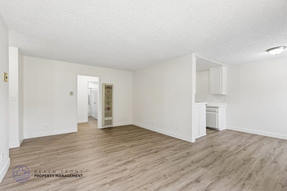 A spacious room with wooden flooring and white walls.