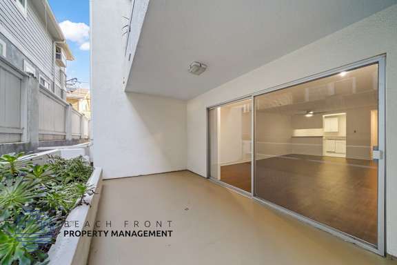 A balcony with a glass door leading to a room with a plant on the left.