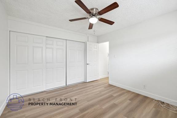A room with a ceiling fan and wooden flooring.