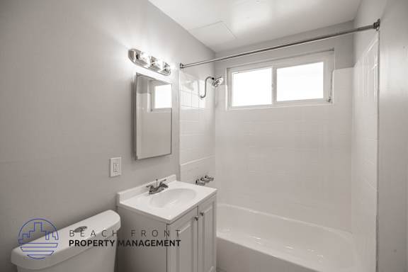 A white bathroom with a sink, mirror, and bathtub.