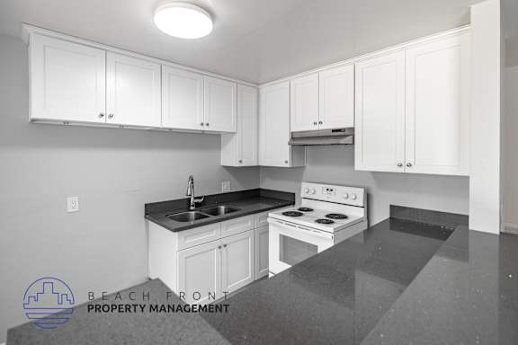 A kitchen with white cabinets and a stove top oven.