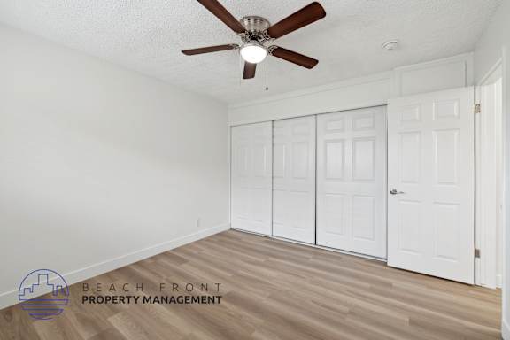 A room with a ceiling fan and wooden flooring.